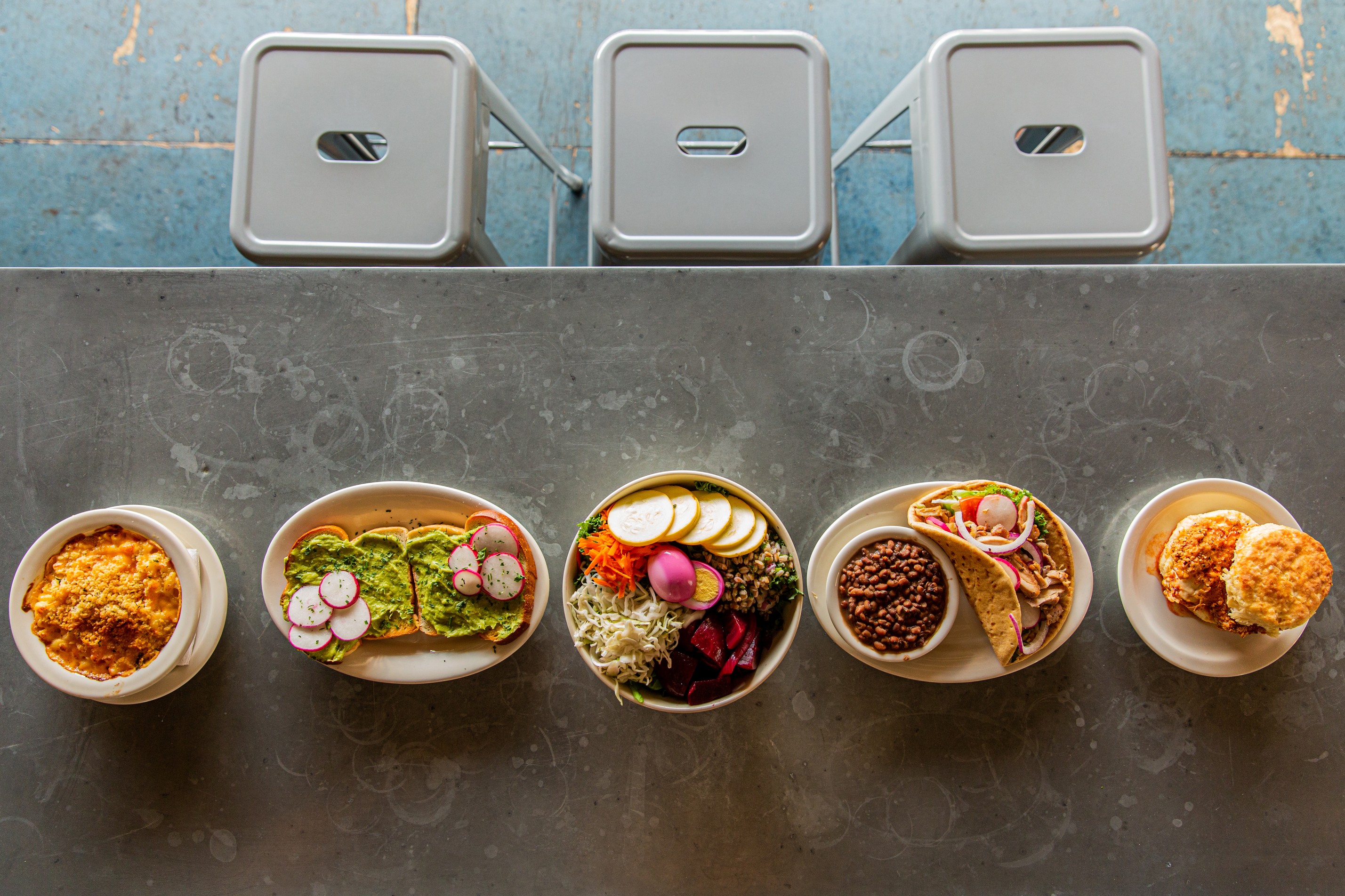 A line up of various breakfast and lunch foods on a counter with barstools for seating