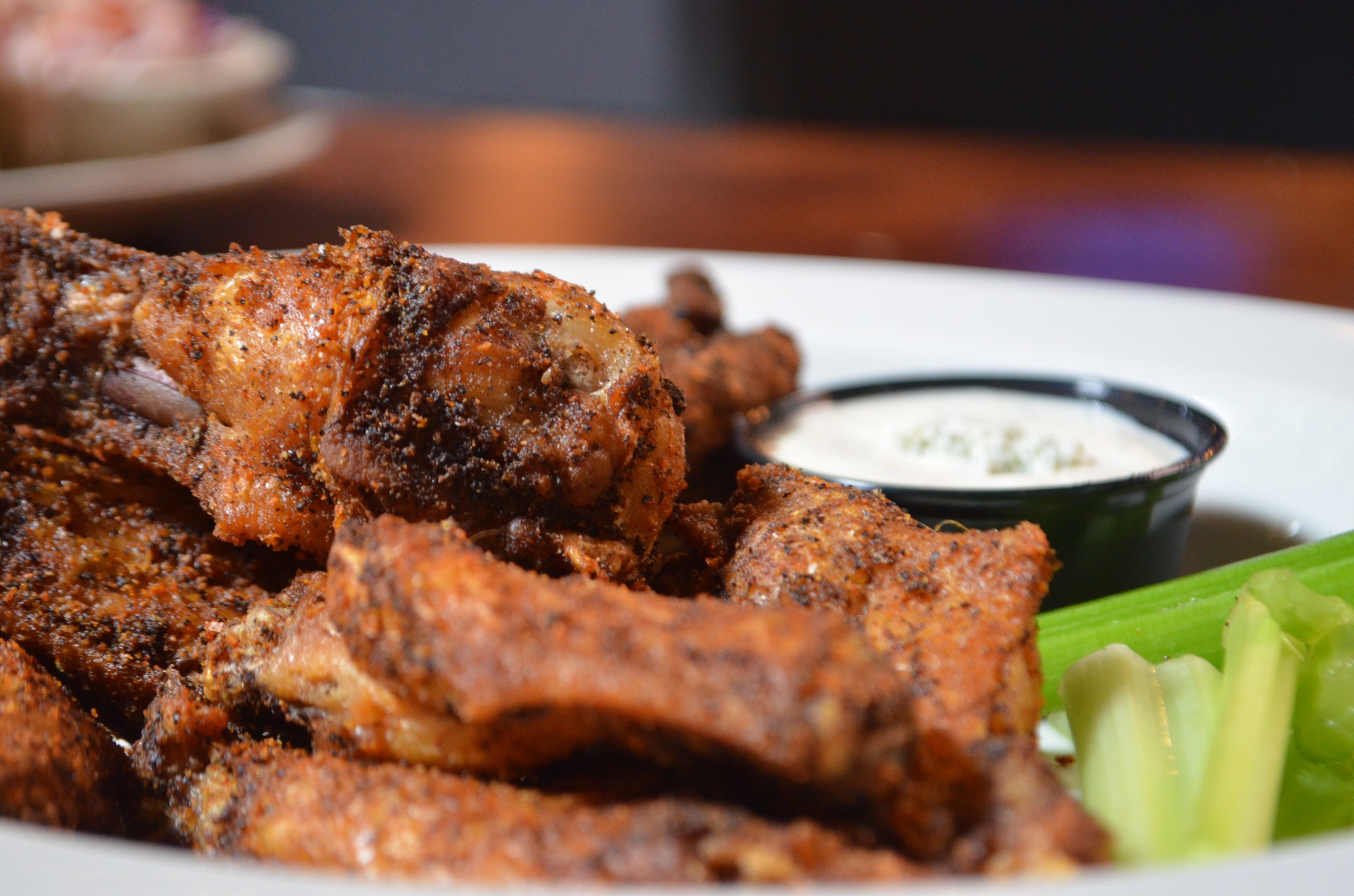 A plate of chicken wings with celery and dipping sauce