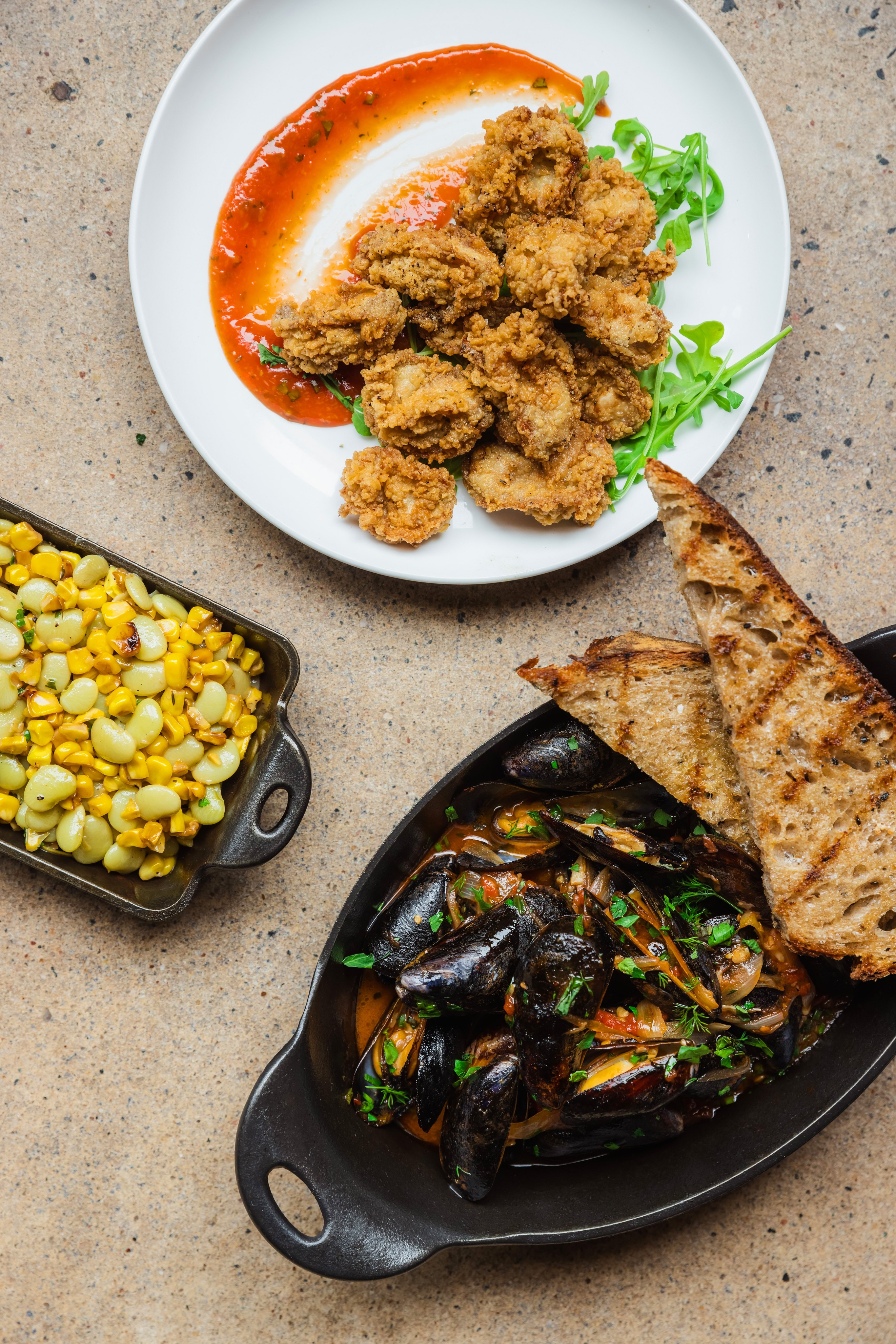 A table of various plates of food including mussels and fried oysters