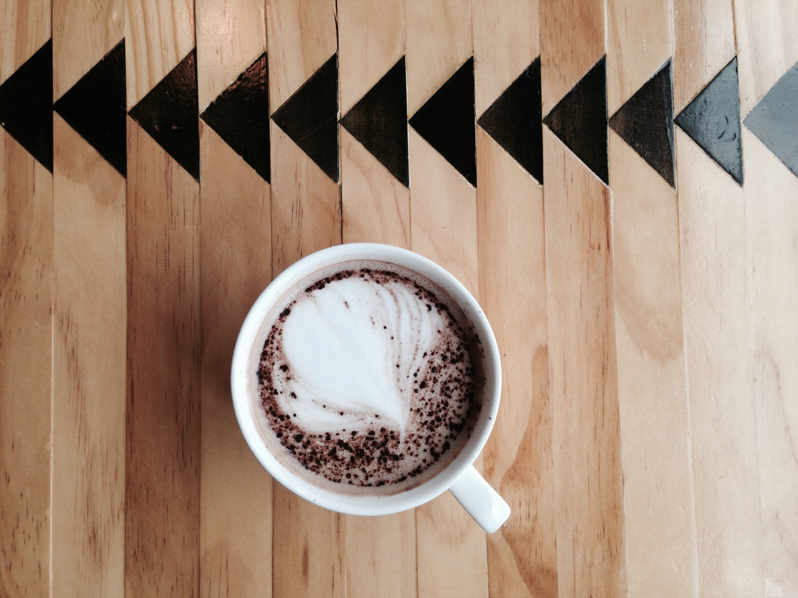 A white ceramic coffee mug filled with coffee on a wooden countertop