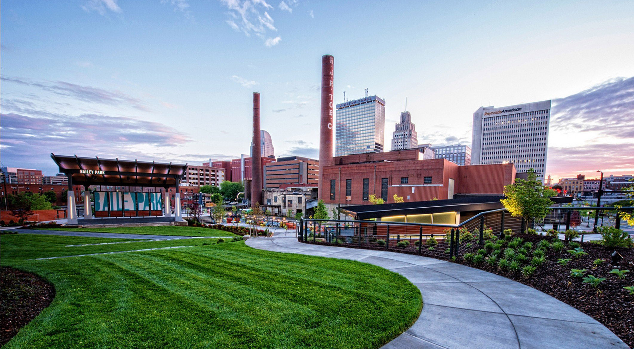A wide range look at Bailey Park, located in the center of downtown Winston-Salem's Innovation Quarter, with the iconic RJR smokestacks in the background.