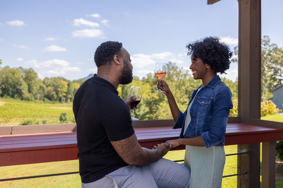 A man and woman enjoy glasses of wine on the patio overlooking the vines at Jolo Winery &amp; Vineyards near Winston-Salem, North Carolina.