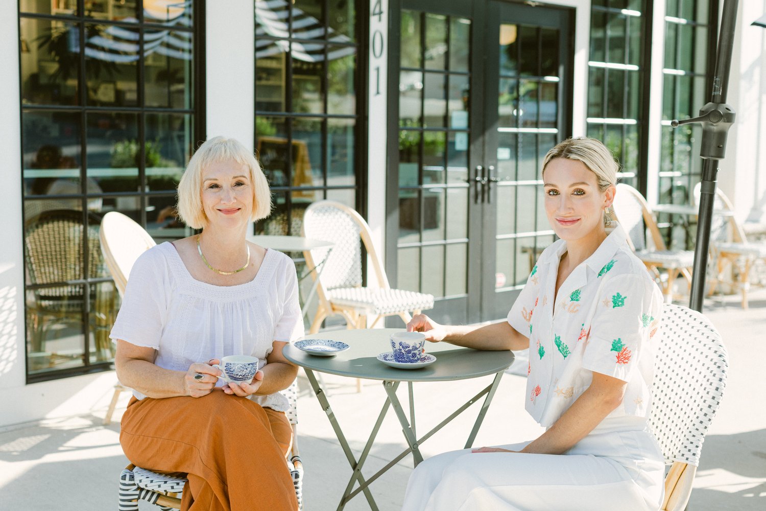 Naomi and Natalie- owners and cofounders of Louie & Honey Bakery in Winston-Salem- sit at a table outside their business.