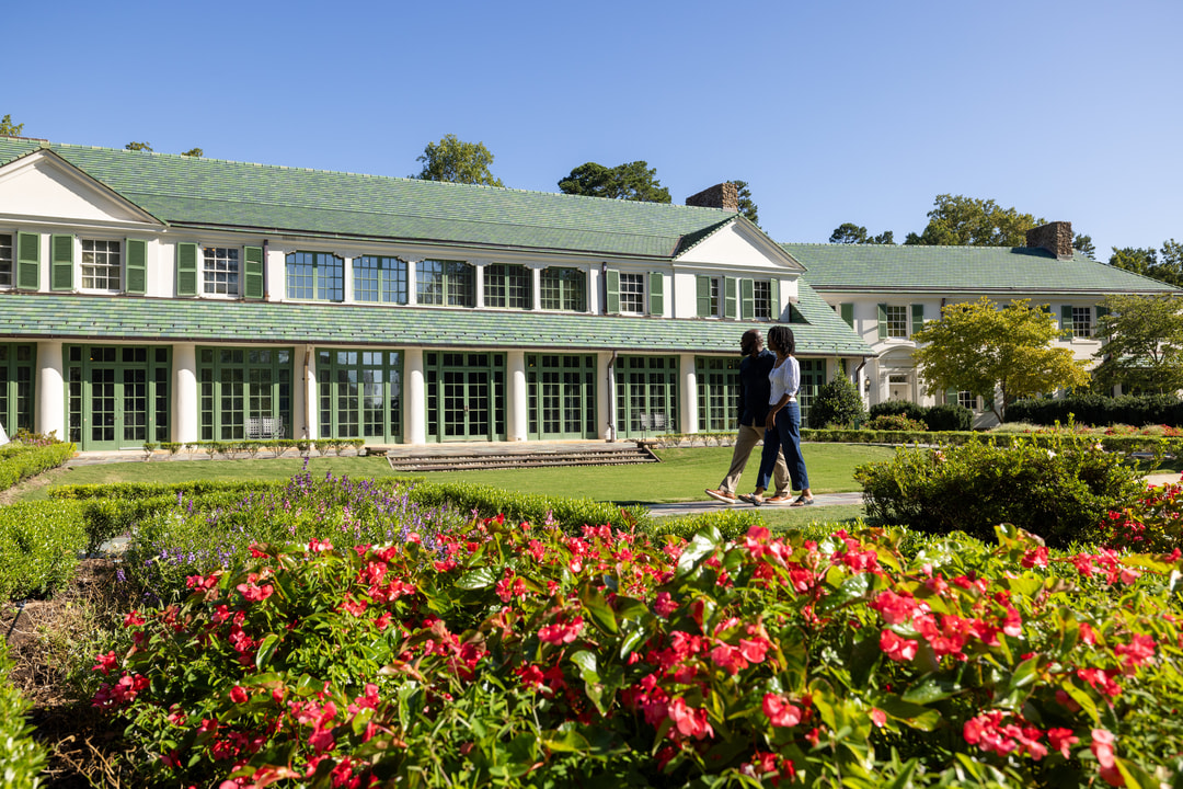 A man and woman tour the Reynolda grounds in front of the Reynolda House Museum of American Art.