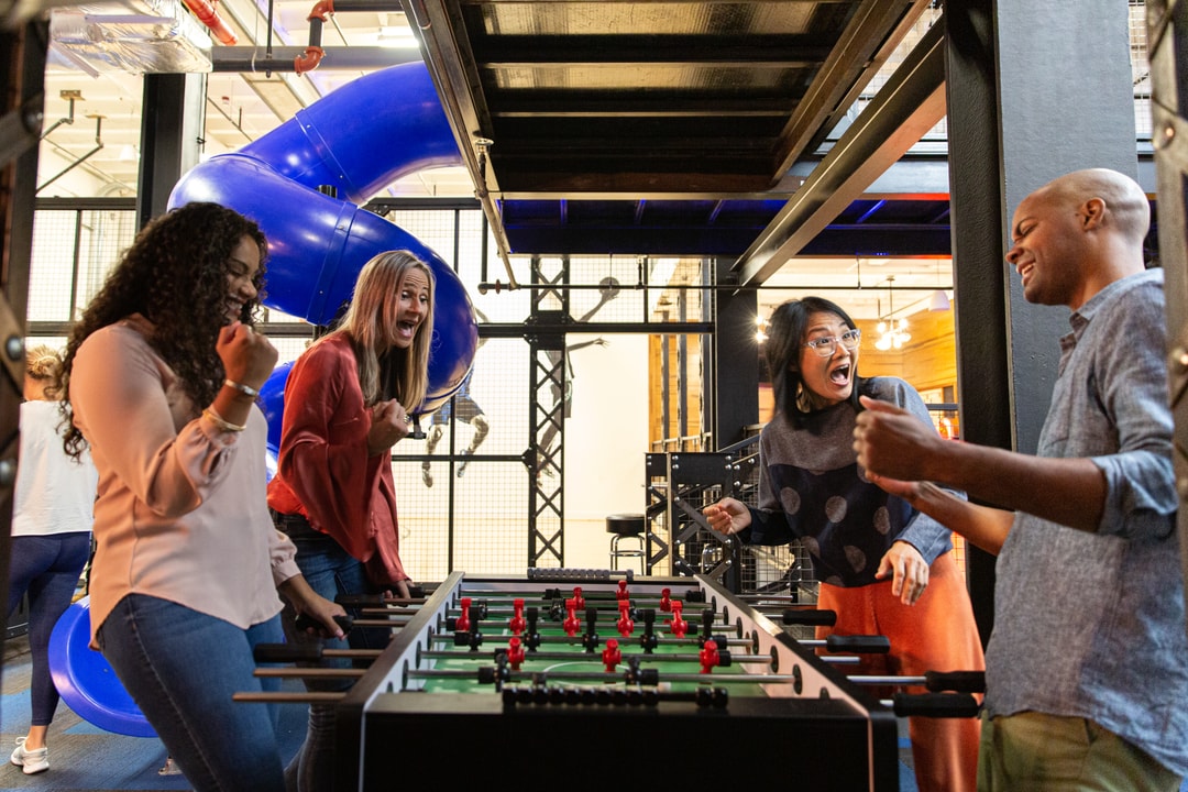 Three women and one man face off at the foosball table in the Kimpton Cardinal Hotel game room.