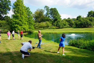 A small group works together in front of the lake at the Graylyn Estate on a team building activity.