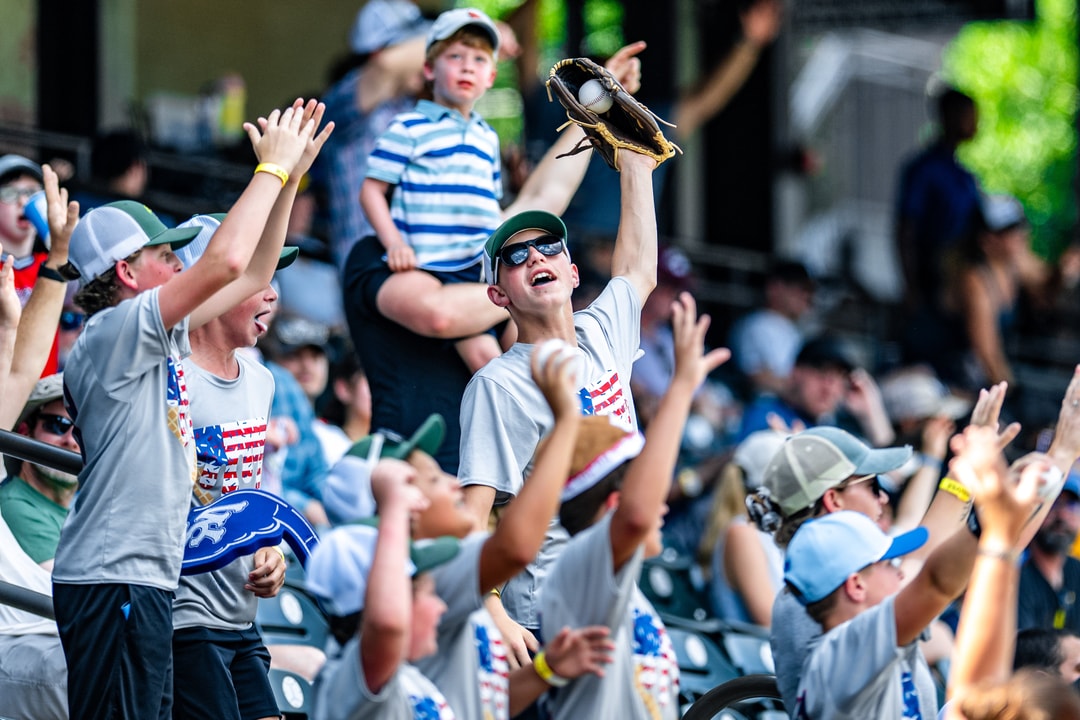 A young child catches a foul ball at a Winston-Salem Dash baseball game.
