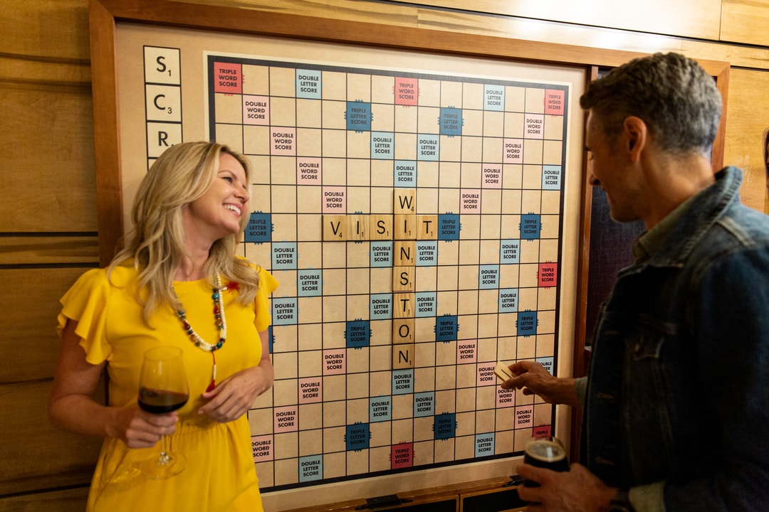 A man and woman play a game of oversized Scrabble in the game room at the Kimpton Cardinal Hotel.