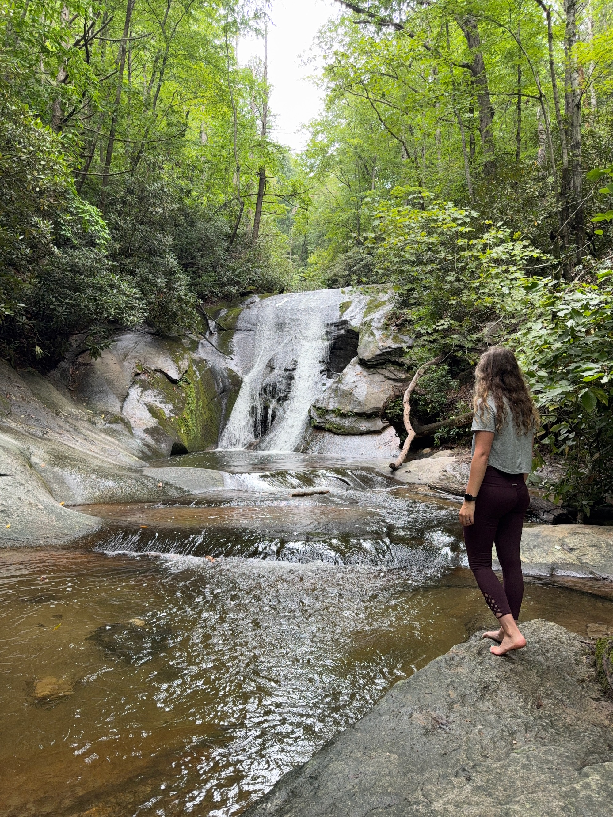 A woman stands and admires Widow Creek Falls Stone Mountain State Park.