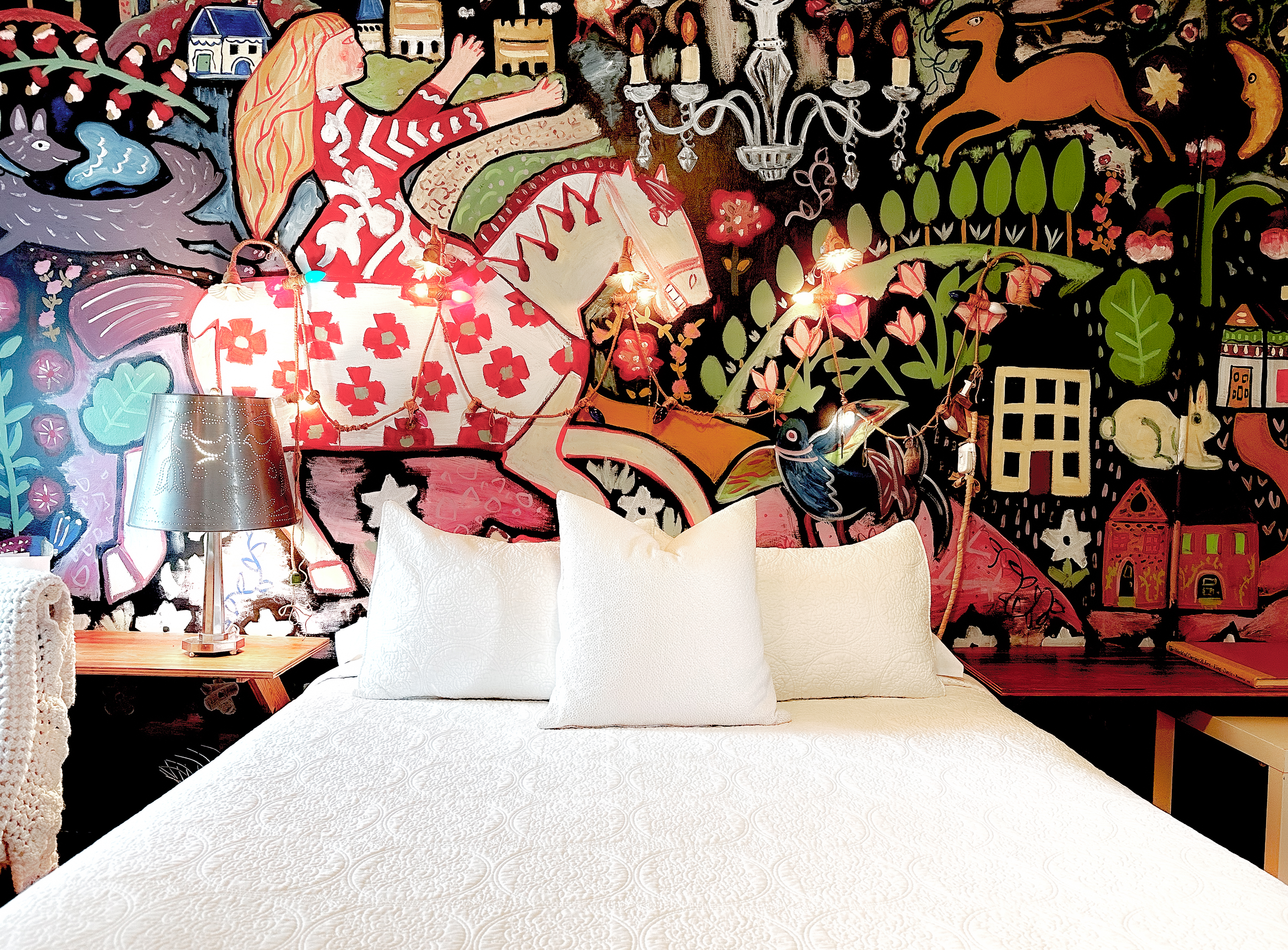 A large mural adorns a wall above a bed in a guest room at the West Salem Art Hotel.