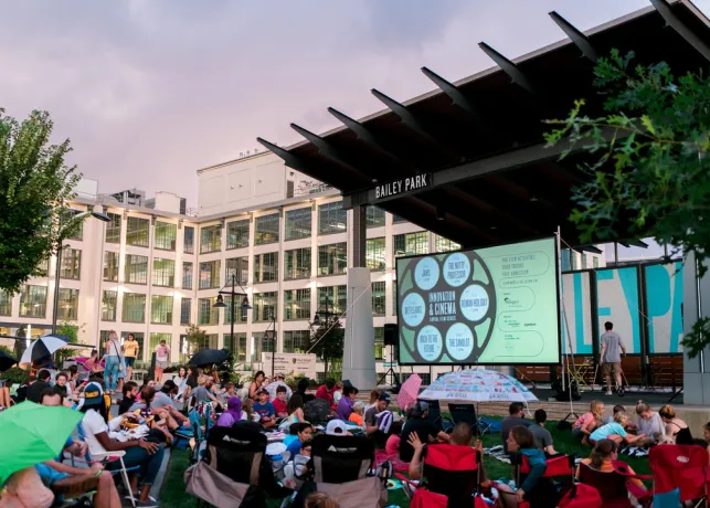 A group of people watching an outdoor movie screening in Bailey Park, Downtown Winston-Salem