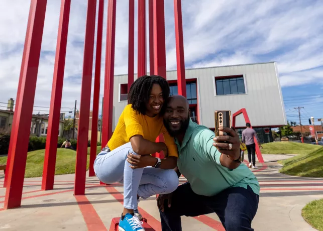 A couple poses in front of an art installation in downtown Winston-Salem