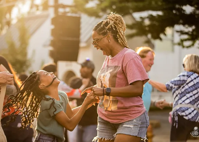 A mother and child dance together at the Summer Music Series in downtown Winston-Salem.