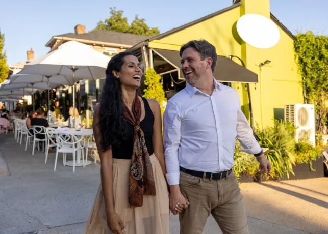A man and woman hold hands walking away from a meal on the patio at Mozelle's restaurant in Winston-Salem