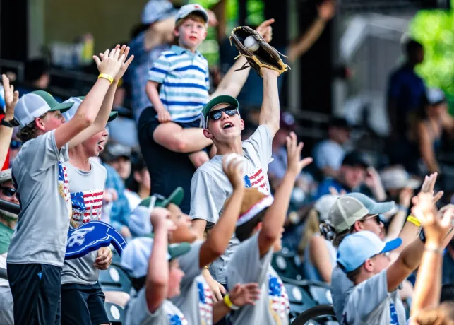 A young child catches a foul ball at a Winston-Salem Dash baseball game.