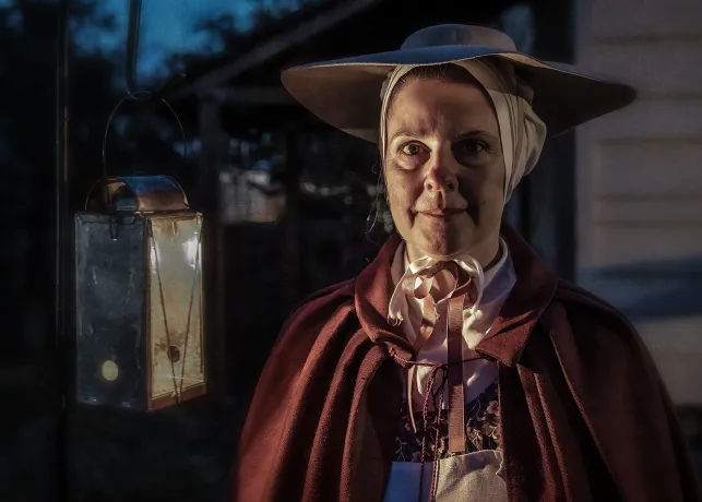 A costumed interpreter at Old Salem Museums & Gardens leads a Halloween Lantern Tour.