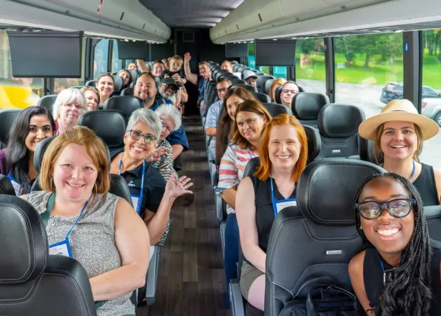 Travelers on a group tour through Winston-Salem smile and pose for a photo inside the bus before heading to their next stop.