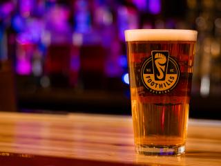 A single pint glass of beer on the bar top at Foothills Brewpub.