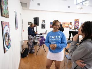 Two women stand in the Delta Arts Center gallery space admiring a piece of art and having a conversation.