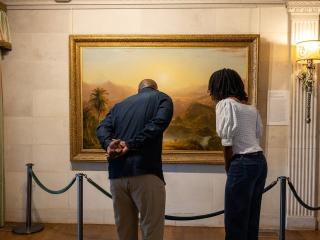 A couple explores the Reynolda House Museum of American Art and stops to look closer at a painting.