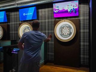 Two men play darts at Millers on Trade sports bar in Winston-Salem.