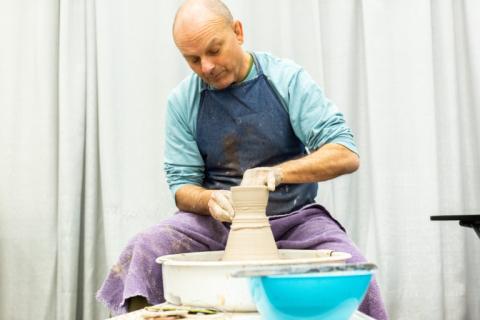 Man creating clay pot on potters wheel