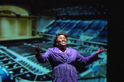 Woman in a purple dress performing on stage at the International black theatre festival