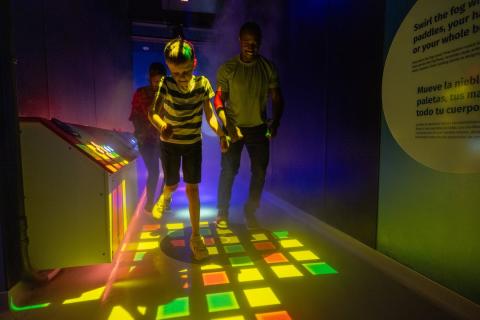 A child runs through an exhibit at Kaleideum Children's Museum in Winston-Salem with two adults close behind him.