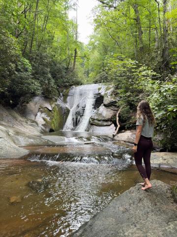 A woman stands and admires Widow Creek Falls Stone Mountain State Park.