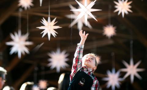 A child reaches up toward the Moravian holiday stars hanging along the top of the Heritage Bridge in Old Salem.