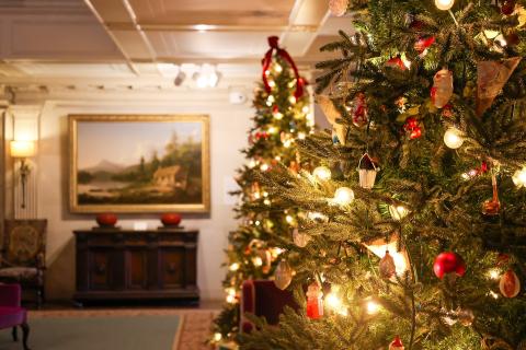 Twinkling lights and ornaments adorn two large Christmas trees, on display in the Reynolda House Museum of American Art.