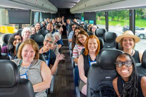 Travelers on a group tour through Winston-Salem smile and pose for a photo inside the bus before heading to their next stop.
