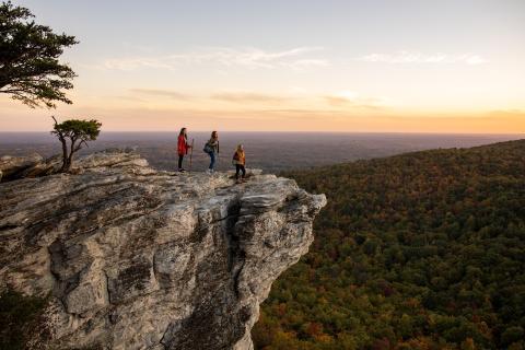 A group of three people admire the sunset from a viewing point at Hanging Rock State Park near Winston-Salem.