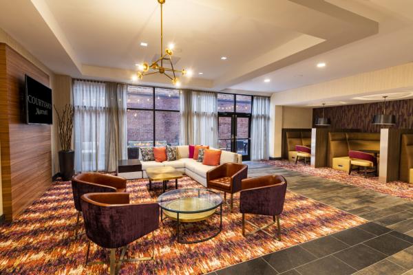 The lounge area offers guests additional seating with a TV, direct access to the Courtyard Patio, and close proximity to the Business Pods and Business Center. Photo 9