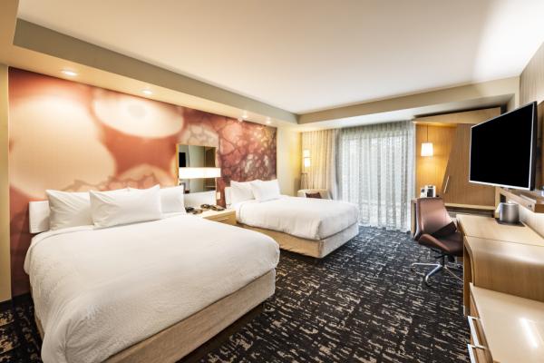 This spacious guest room features two luxurious queen-size beds surrounded by a fresh, progressive design that provides plenty of outlets and comfortable spaces for both relaxation and work. Photo 15