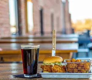A fried chicken sandwich with tater tots and a pint of dark beer at Earl's in Winston-Salem.