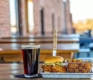 A fried chicken sandwich with tater tots and a pint of dark beer at Earl's in Winston-Salem.