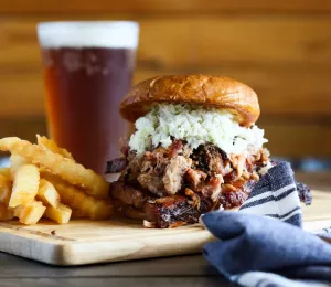 A plate of pulled pork barbecue with fries and a pint of beer, served at Little Richards Bar-n-Que in Winston-Salem, North Carolina
