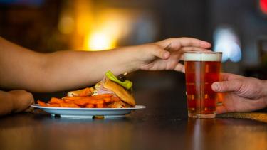 A plate of food and a pint of beer being handed to a bar patron across the bar at Small Batch Beer Company.