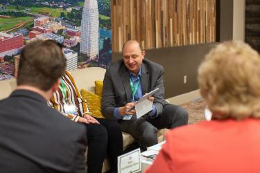A group of meeting planners sit together at a sitting area during a conference to discuss meetings and conventions in Winston-Salem.