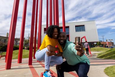 A couple poses in front of an art installation in downtown Winston-Salem