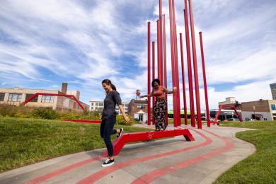 Two women walking through Artivity on the Green Park in downtown Winston-Salem.
