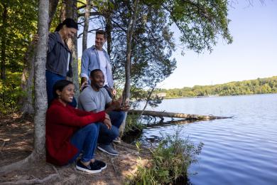 Four people sit at the shoreline while exploring the Salem Lake Trail in Winston-Salem.