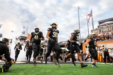 The Wake Forest University football team runs on the field at the opening of a game.