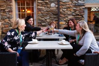 A group of four women click their glasses while dining at the Graylyn Estate Hotel and Conference Center in Winston-Salem, North Carolina.