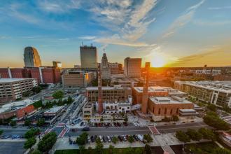 A wide aerial view of the downtown Winston-Salem skyline at sunset.
