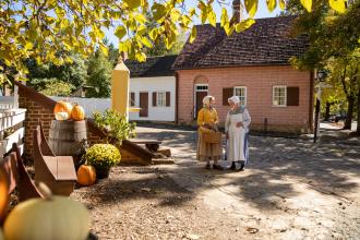 Two costumed interpreters walk the streets of Old Salem Museums & Gardens during the fall.