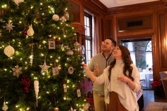 A couple admires a large, decorated Christmas Tree on display at the Graylyn Estate in Winston-Salem.