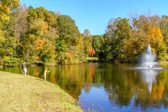 Two people fish from the side of small pond, located inside Tanglewood Park in Clemmons, NC.