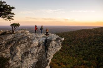 A group of three people admire the sunset from a viewing point at Hanging Rock State Park near Winston-Salem.